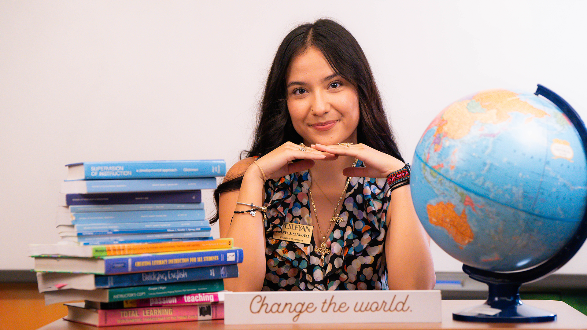 An education student posed around books and a globe