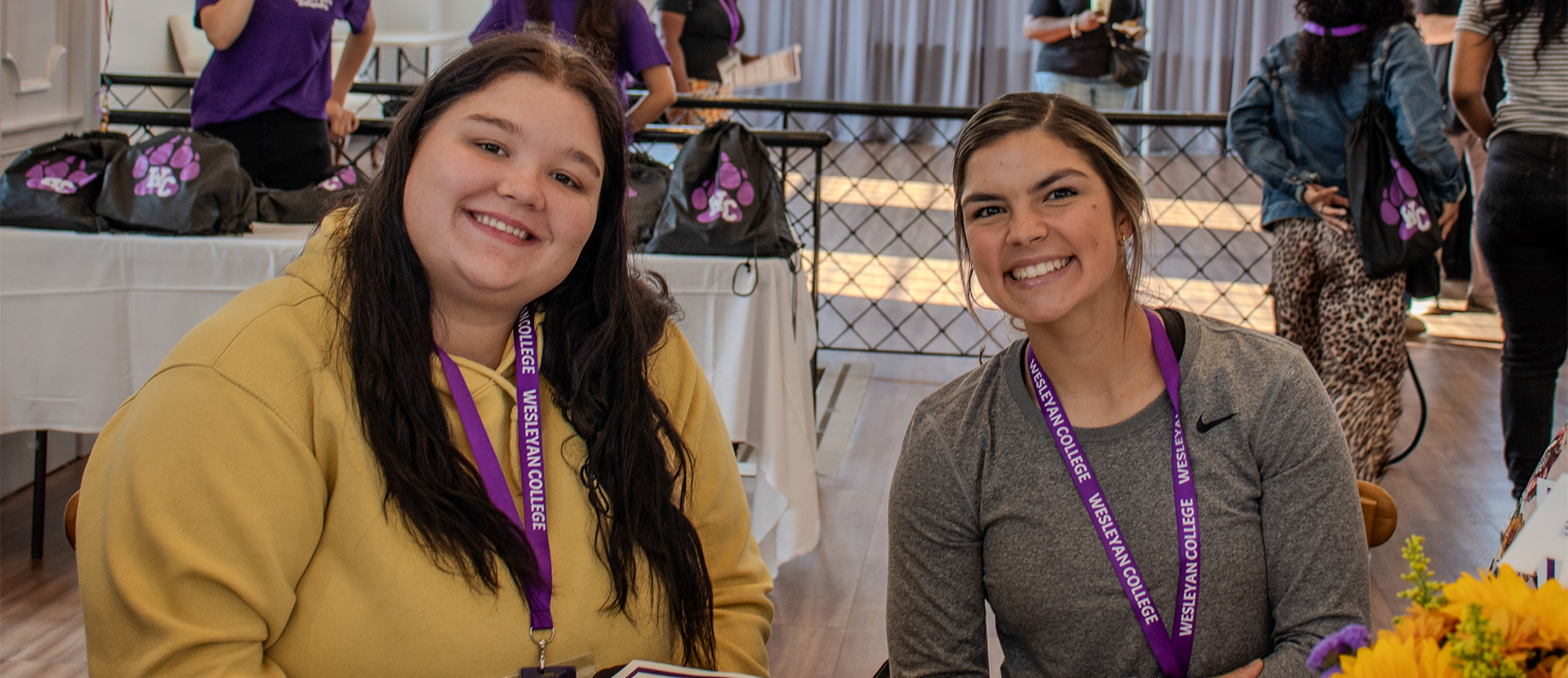 two students at a table smiling