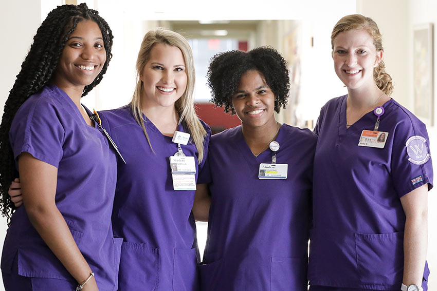 Four Nursing students in Munroe Science Center hall.
