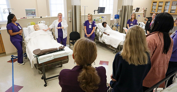 Professor instructing students in Nursing lab.